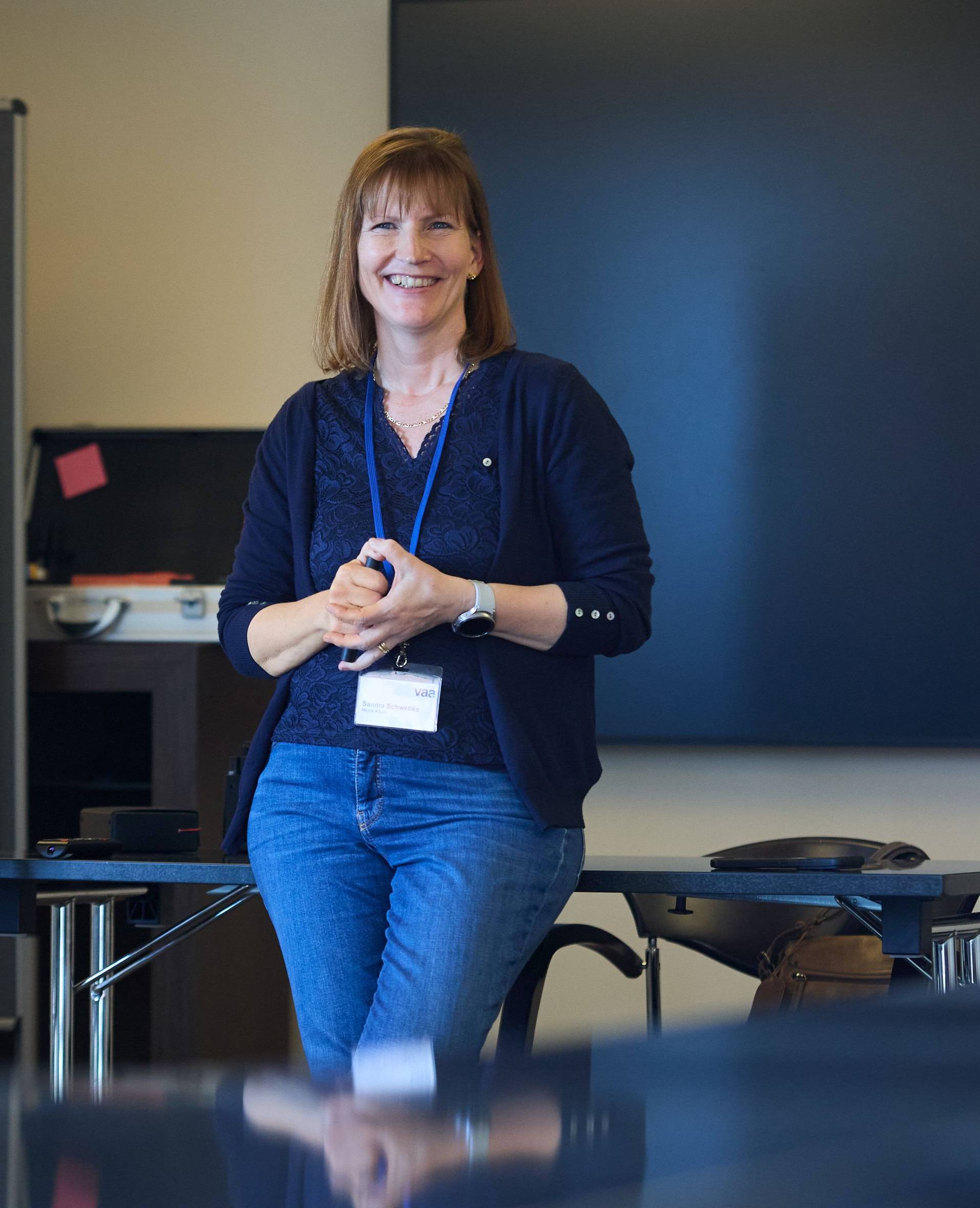 Sandra Schwebke steht an einen Tisch gelehnt vor einem Flipchart.