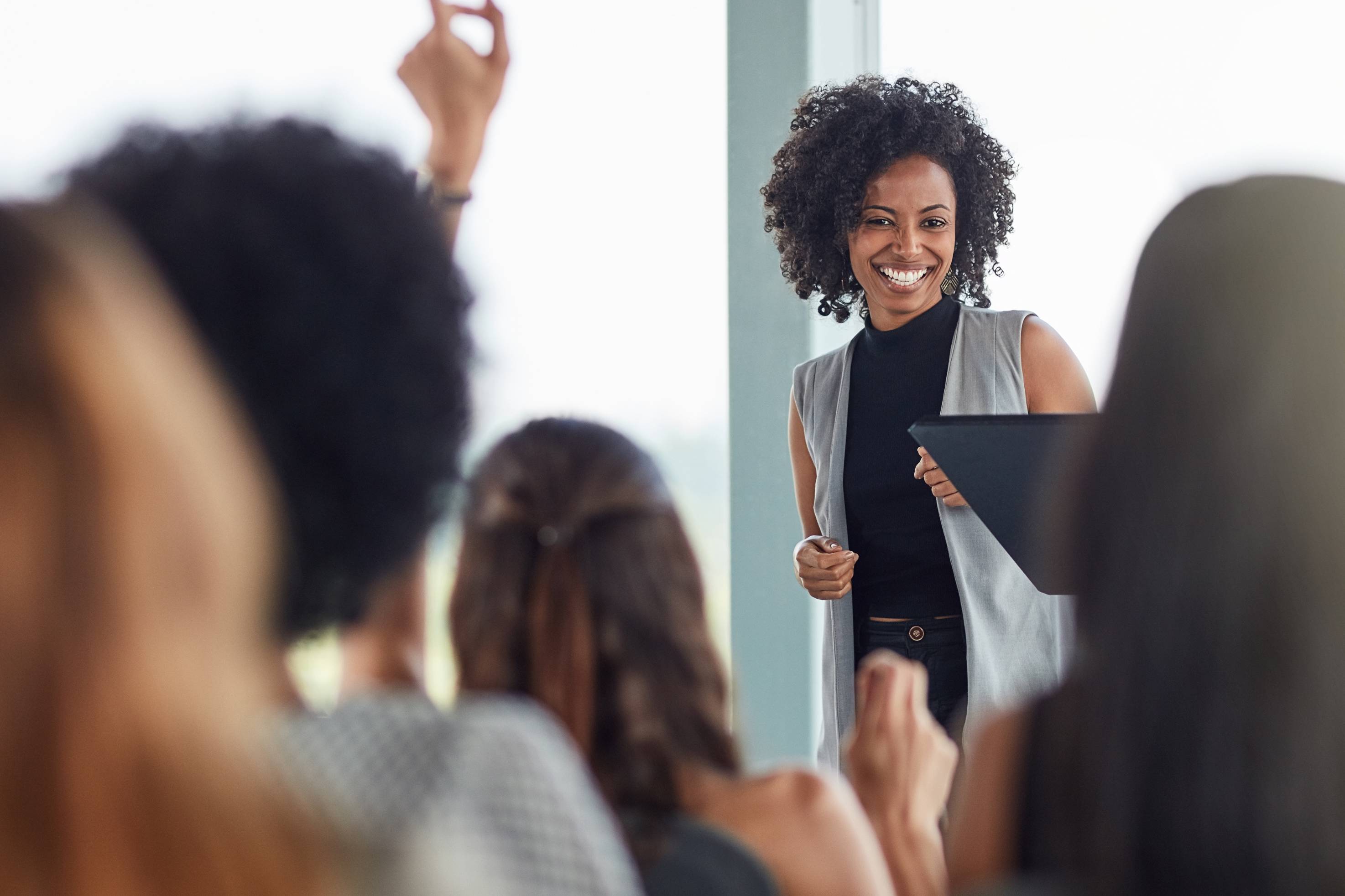 Symbolbild: Workshopsituation aus dem Publikum mit einer Referentin vorn am Fenster.