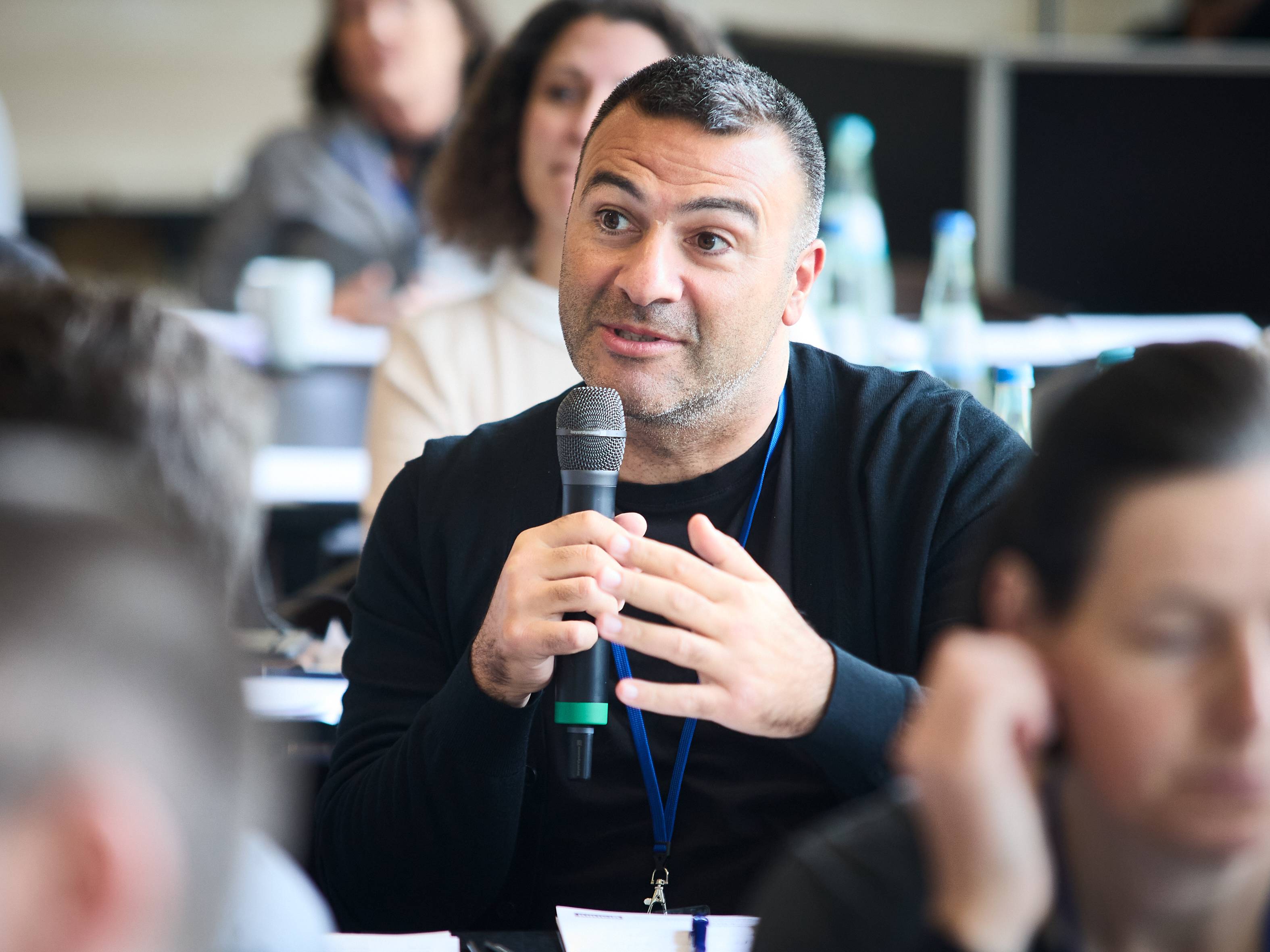 Roche-Betriebsratsmitglied Yasin Güler im Plenum in ein Mikro sprechend.