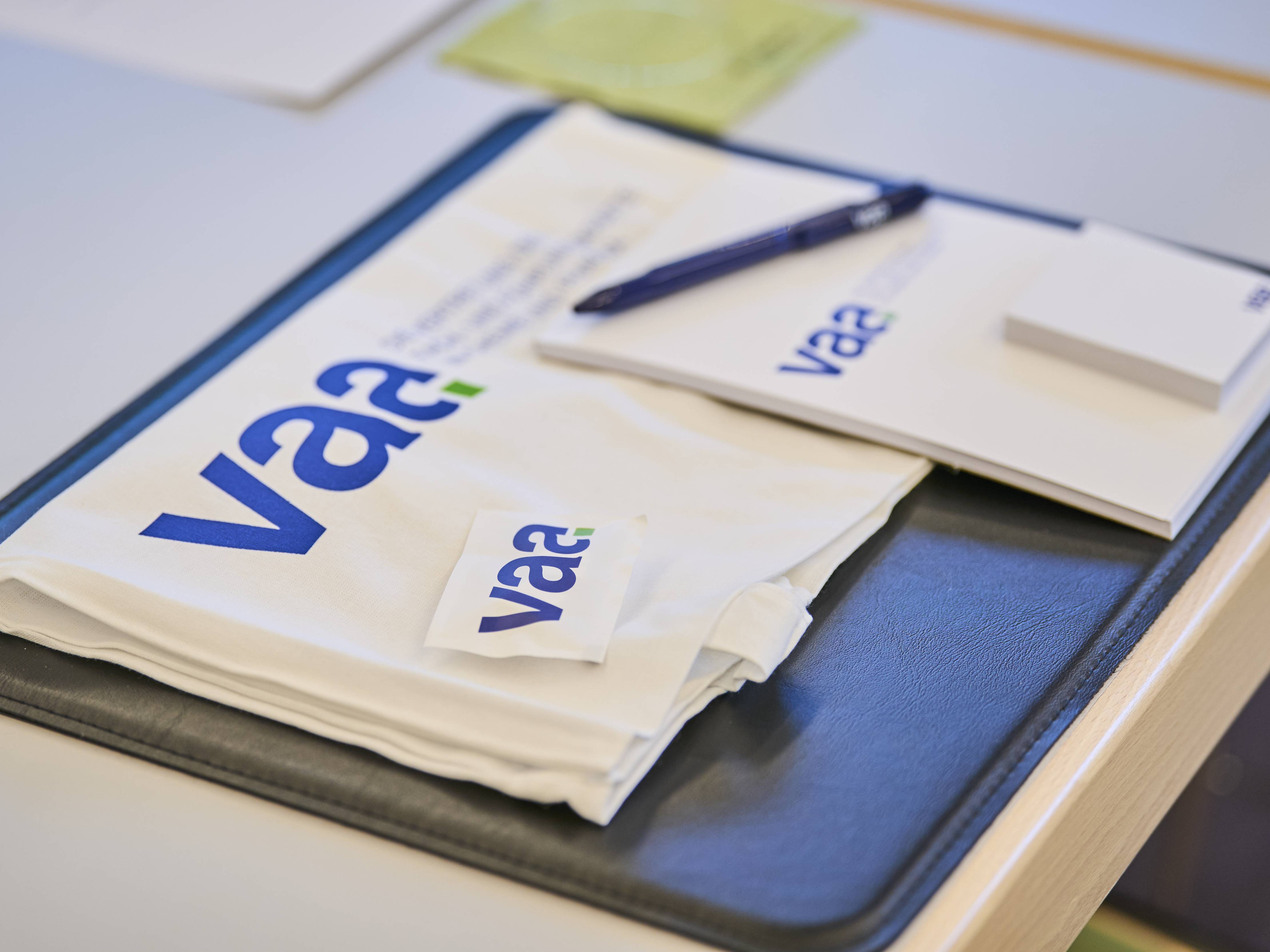 Auf einem Tisch: VAA Beutel, darauf ein Block mit VAA Logo, ein Kugelschreiber und ein Traubenzucker mit VAA Aufdruck.