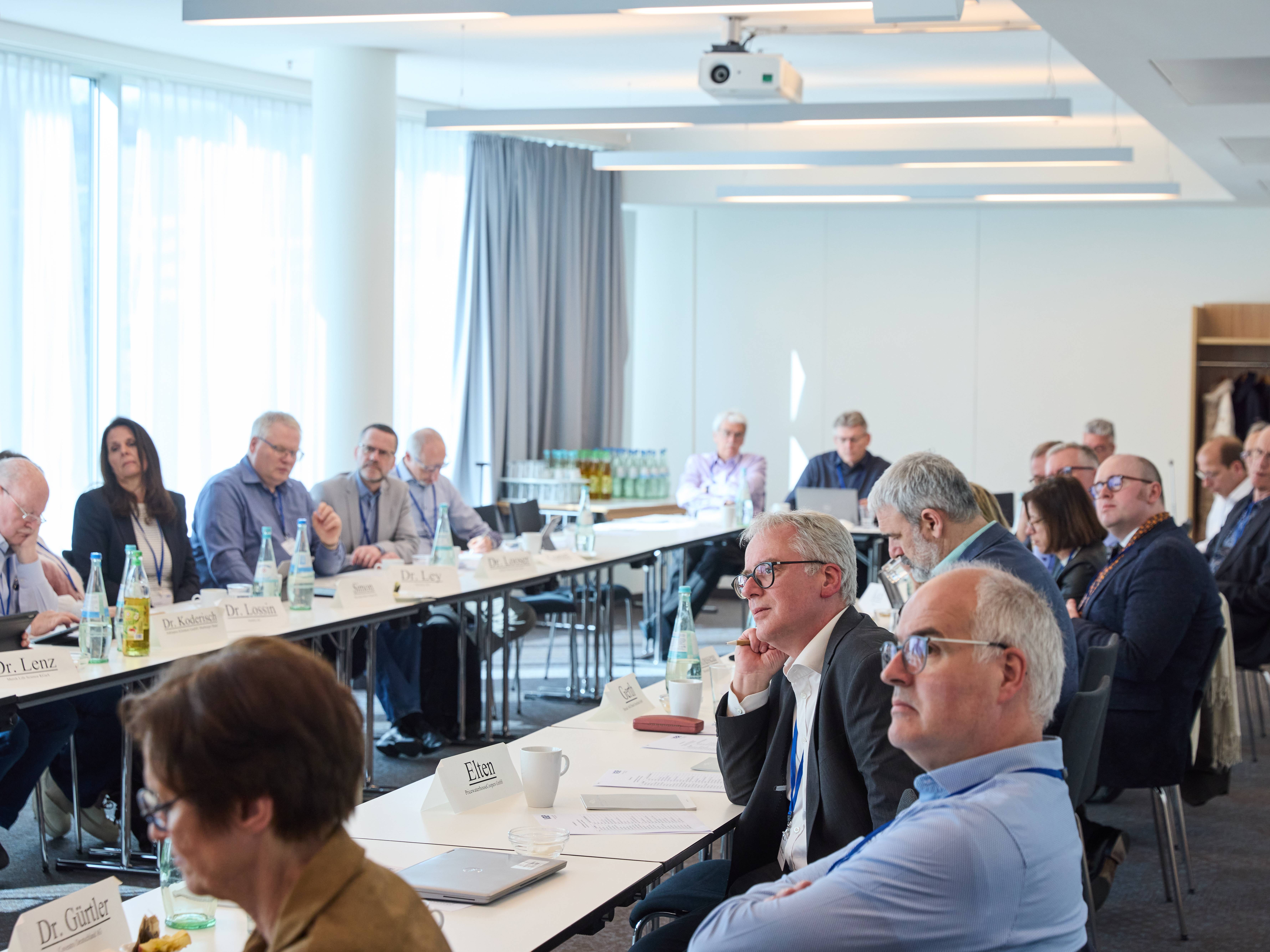 Das Plenum in einem hellen Raum, der Blick geht nach links (vorne).